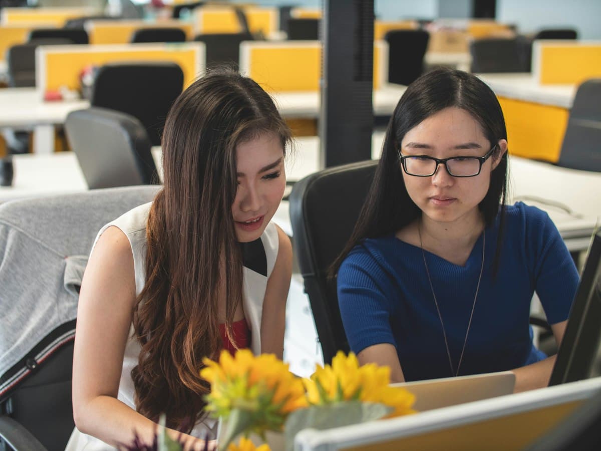 Two colleagues reviewing work together at a laptop